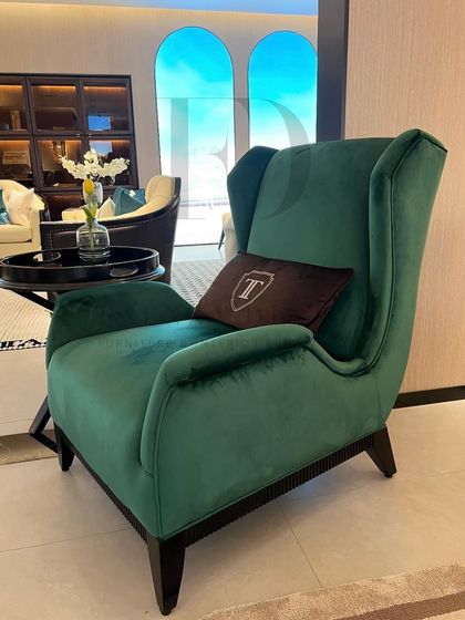 A stately wingback chair upholstered in a luxurious emerald green velvet. Its grand proportions and classic silhouette make it a perfect statement piece for a formal living room or library.
