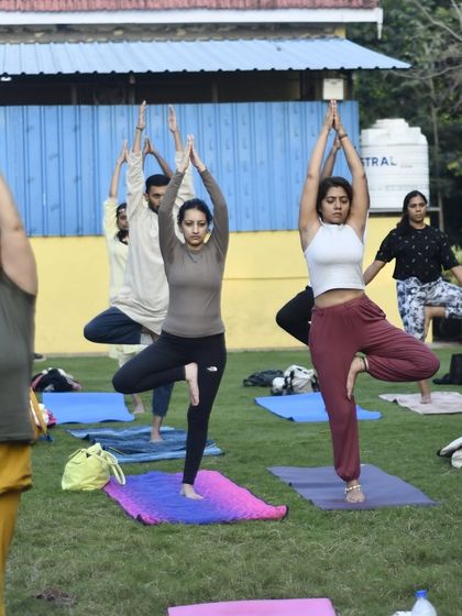 Participants holding Vrikshasana (Tree Pose) during an outdoor session. This balancing posture teaches us stability and grace, mirroring the strength of the nature surrounding us.