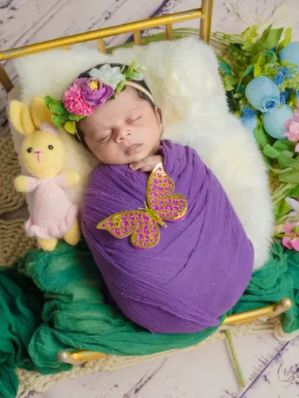A butterfly has landed. This beautiful overhead shot shows a baby sleeping on a floral bed, adorned with a single butterfly.