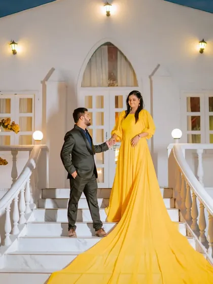 A beautiful composition on the steps of the white chapel set. The long, flowing yellow gown cascades down the stairs, creating a visually stunning and memorable photograph.