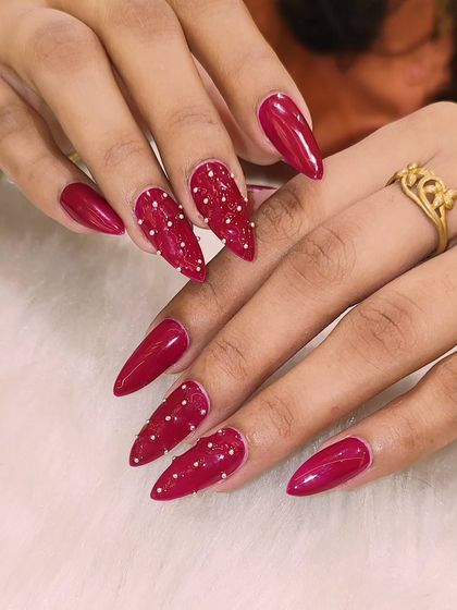 Another angle of the dramatic red stiletto nails. The combination of the glossy red and the matte, textured pearls creates a stunning contrast.