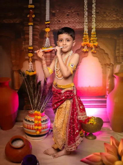 A serene portrait of a young boy as Krishna, playing his flute. Our studio setup, complete with peacock feathers and earthen pots, creates an authentic Vrindavan atmosphere for these divine photoshoots.