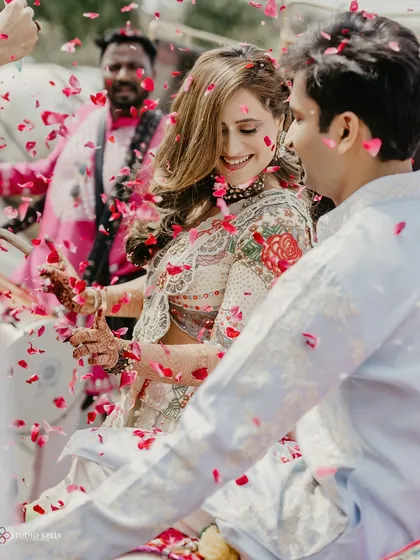 A shower of rose petals rains down on the couple as they enjoy their grand entry in a horse-drawn carriage.