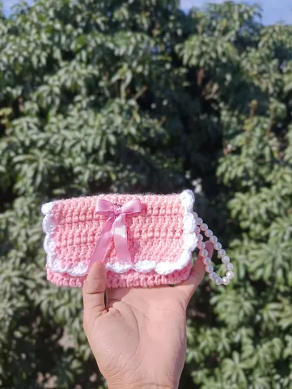 A sweet pink pocket purse with a white scalloped edge and a satin bow. This design is very popular for event giveaways and college fests.