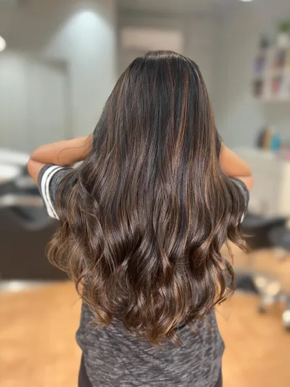 A classic caramel brown color that adds warmth and richness. The hair is styled in soft waves to show off the beautiful dimension.