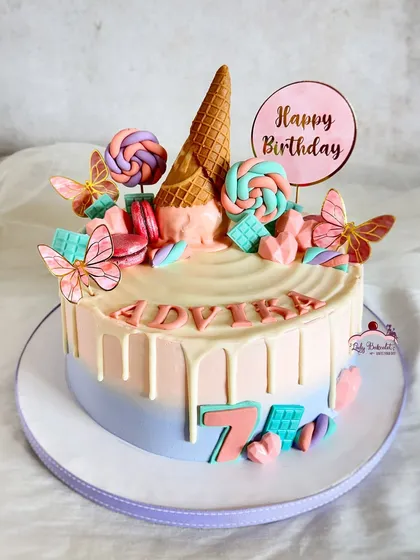 A pretty pastel candyland cake, loaded with an ice cream cone, lollipops, macarons, and edible butterflies.