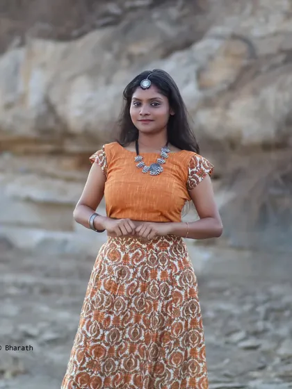 A classic portrait pose in the same outfit, showing the full look with the printed skirt and orange crop top.
