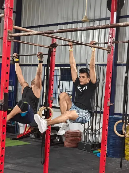Two athletes holding a challenging L-sit on the pull-up bars. This static hold is a brutal test of core strength and mental fortitude.