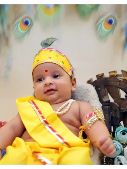 A close-up portrait of a smiling baby during the Krishna photoshoot. This image highlights the baby's happy expression and the details of the costume and tilak.