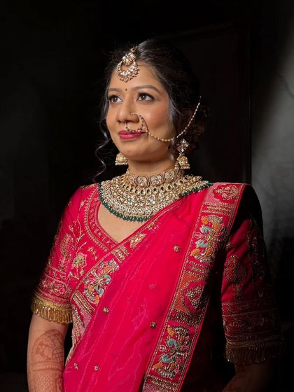 A dramatic portrait with focused lighting. The makeup looks stunning even in low light, with her features beautifully defined against the dark background.