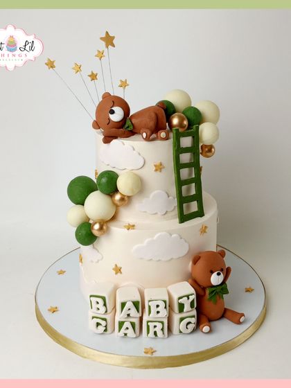 A dreamy baby shower cake with a teddy bear theme. This two-tiered design features cute bears, fluffy clouds, stars, and a ladder reaching for the sky.