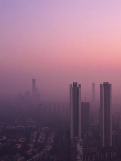 A close-up on two skyscrapers piercing through a thick, purple haze during a Mumbai winter sunset.