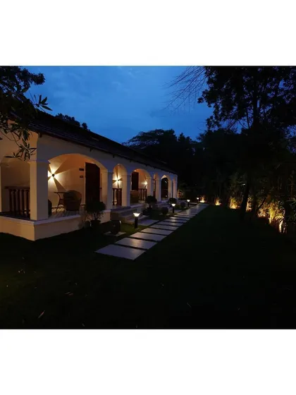 The right lighting can completely transform an outdoor space after sunset. Here, I used a combination of subtle uplighting on the trees and warm, welcoming lights along the pathway and within the verandas. This strategic landscape lighting design enhances the building's classic architecture and creates a safe, magical ambiance for evening enjoyment.