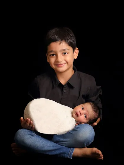 A classic sibling portrait against a simple black background. This style puts all the focus on the children's expressions and the bond between them.