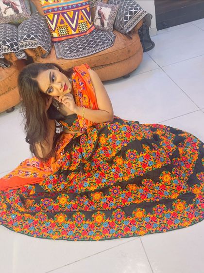 A graceful pose in the black and orange Garba lehenga, highlighting the vibrant colors.