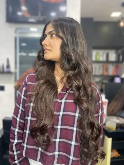 This client's very long hair is styled in soft, flowing waves, creating a romantic and beautiful look.