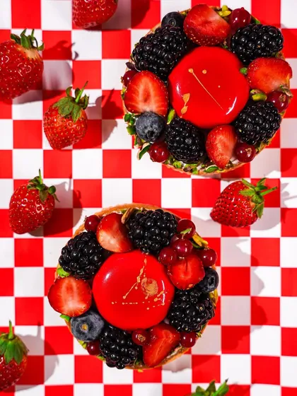 A flatlay of two berry tarts on a red and white checkered pattern. The graphic composition and vibrant colors create a bold and playful image, perfect for social media.