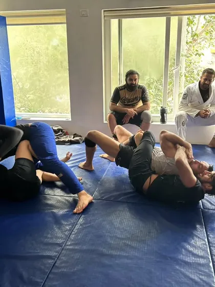 Two students roll during an open mat session while others watch and wait for their turn. This is where you test your skills and learn from your teammates in a relaxed but focused environment.