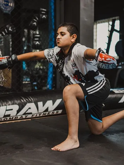 A young fighter practices a pose from the Wai Kru, learning the traditions of Muay Thai.