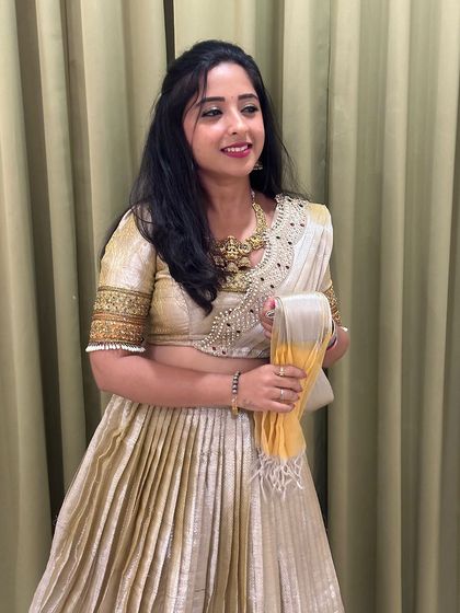 Singer Ananya Prakash looks radiant in this cream and gold half saree. The pleated skirt has a beautiful shimmer, and the blouse is adorned with intricate handwork around the neck and sleeves.