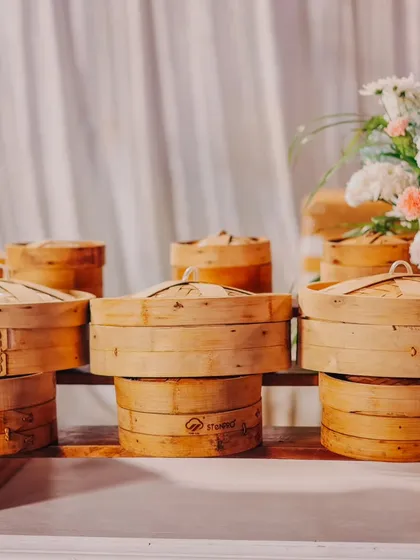 A rustic and charming presentation of steamed dim sum in traditional bamboo baskets. This setup adds an authentic touch to the dining experience at any event.