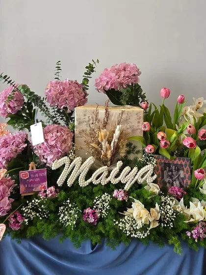 Personalization is at the core of what I do. This arrangement features the name 'Maiya' crafted from pearls, nestled in a bed of lush pink hydrangeas, tulips, and orchids, making the gift uniquely hers.