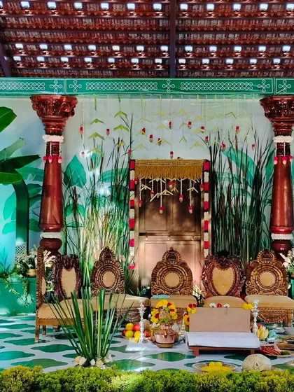 Every detail of a traditional ceremony is important. This South Indian wedding stage combines a hand-painted backdrop with carved wooden seating, banana leaf accents, and marigold flowers for a truly authentic feel.