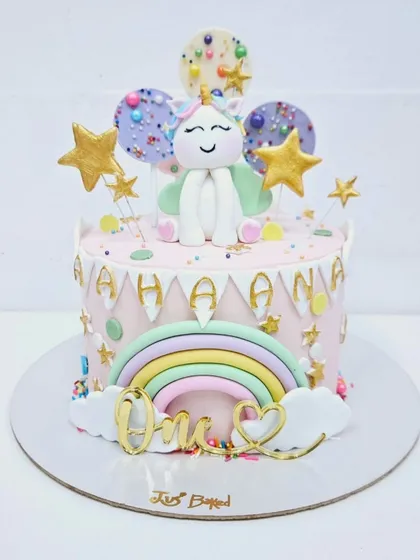A whimsical unicorn cake for a first birthday. This design features a pastel rainbow, fluffy clouds, and a cute unicorn topper, all brought together to celebrate a magical "One" year milestone.