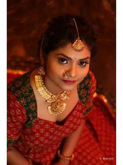 Another powerful high-angle shot, capturing the model's direct gaze. The focus is on the face, makeup, and the heavy gold necklace.