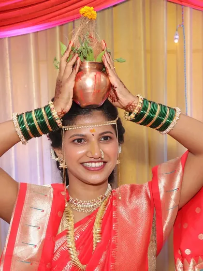 A beautiful ritual during a Maharashtrian wedding. The bride holds a kalash, and her smile is infectious. The simple makeup and traditional attire are perfect for these moments.
