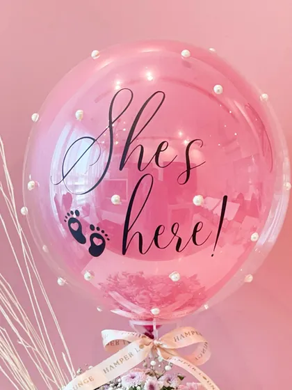 A close-up of the "She's here!" balloon, adorned with delicate pearls. It’s these small, thoughtful details that make a gift feel truly special and luxurious.