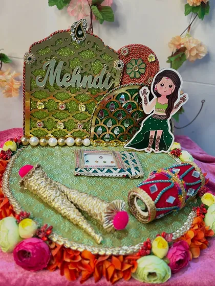 Enhance your Mehendi celebrations with this beautiful platter, where tradition intertwines with vibrant artistry. It features a cute caricature, a mini dholak, and henna cones, making it a perfect addition to your special day.