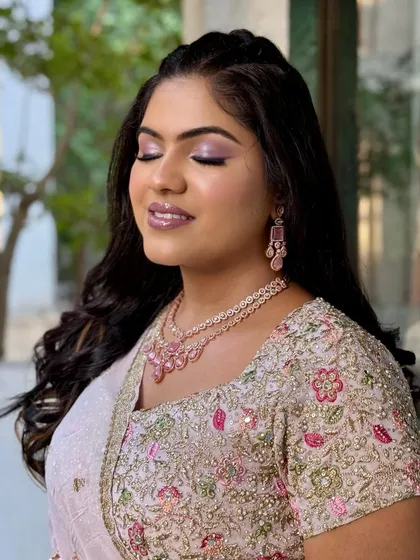 A serene, smiling portrait. The makeup enhances her features and complements her pink jewellery.