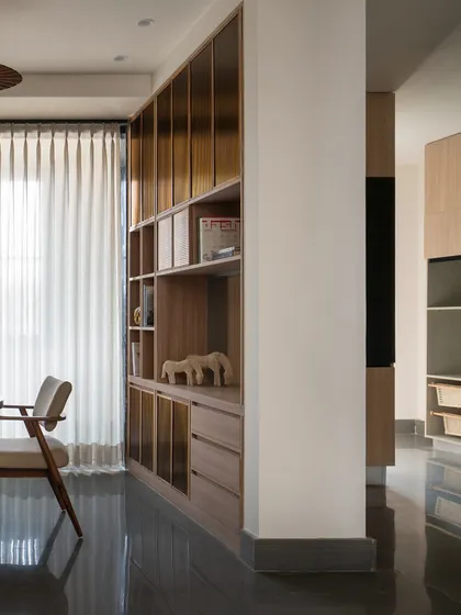 A view of the custom shelving that anchors the living and dining spaces. The unit is finished in a warm timber, with fluted glass panels that add a layer of texture and refinement.