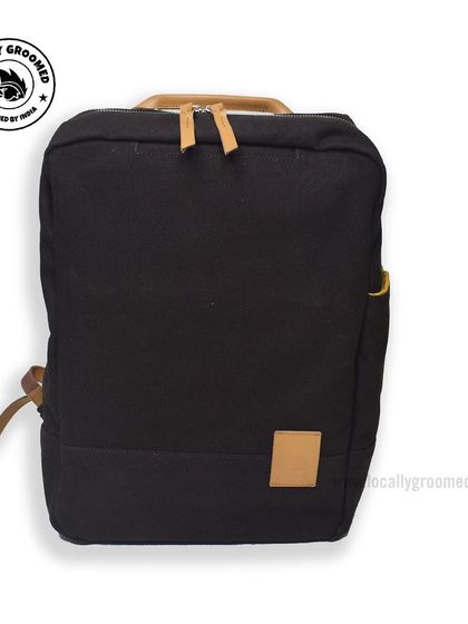 A minimalist black canvas backpack with tan leather accents. This stylish design is perfect for brands looking for a modern, understated look.