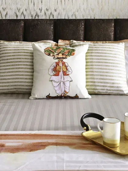 We believe in adding touches of personality through decor. A quirky, illustrated cushion adds a playful element to this otherwise serene bedroom, demonstrating how small details can bring a space to life.