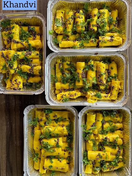 A large order of delicate, savory Khandvi rolls, garnished with mustard seeds and fresh coriander.