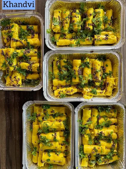 Freshly prepared Khandvi, a savory Gujarati snack made from gram flour, rolled up and garnished with cilantro and mustard seeds.
