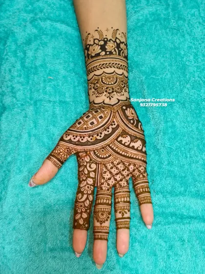 A close-up of one hand, highlighting the detailed work with tiny elephants and floral patterns.