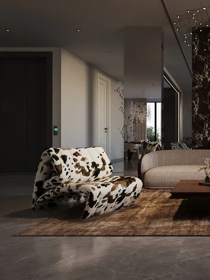 A playful armchair with a cow-print pattern adds a touch of unexpected personality to the family lounge. It sits opposite a dramatic, V-shaped stone column that divides the formal and informal living areas.