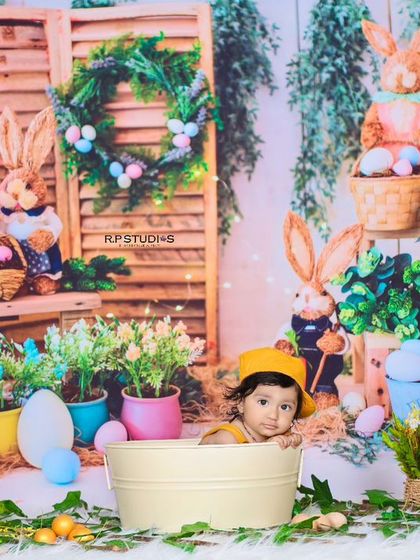 A full view of the rustic bunny garden setup, with the baby looking out from a bucket. The wooden shutters, potted plants, and bunny figures create a complete and charming scene.