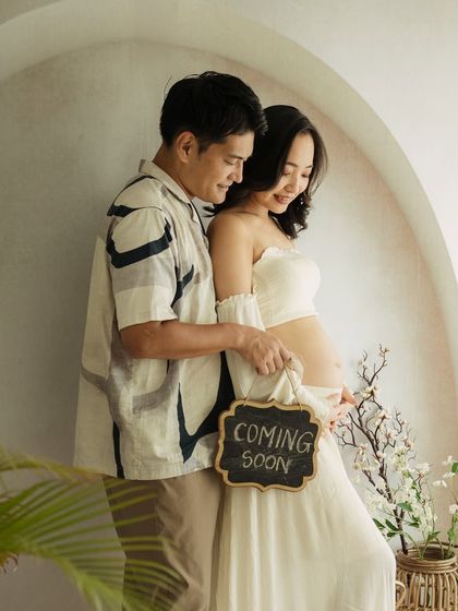 "Coming Soon." A classic announcement shot, made beautiful by the couple's gentle interaction and the soft, airy studio light.