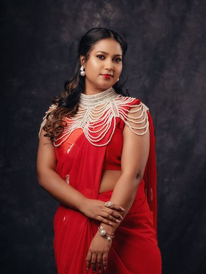 An elegant and regal portrait in a red saree. The statement pearl jewelry adds a touch of high fashion to the traditional look.