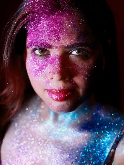 A direct and intense close-up of the glitter makeup. Her eyes are the focal point, drawing the viewer into this colorful and artistic world.