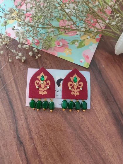 These hand-painted earrings are shaped like traditional arches and feature intricate designs with bead drops. They are available in both green and red, perfect for festive or wedding attire.
