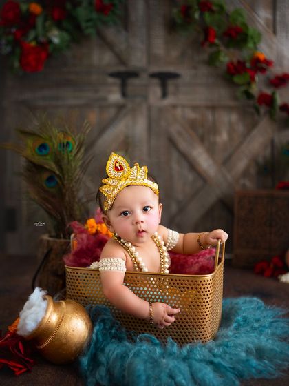 A tiny baby Krishna peeking out of a basket, looking absolutely adorable.