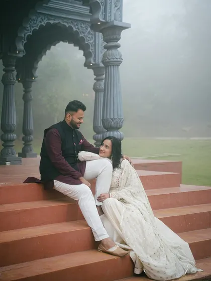 A candid moment captured on the steps of the Indian palatial set. The terracotta colored stairs contrast beautifully with the grey stone pillars and the soft, foggy backdrop.