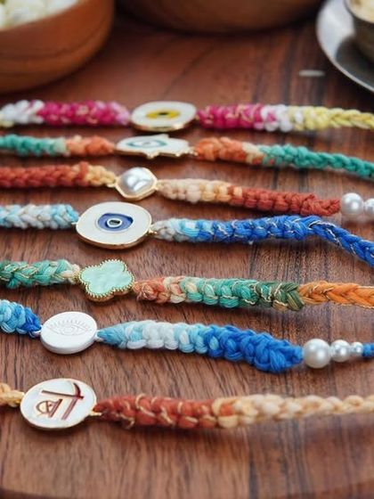 A variety of my charm rakhis laid out. Each one is handcrafted with colorful cotton yarn.