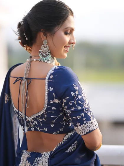 The back view of this bride's look is just as stunning, showing the elegant low bun with accessories and the beautiful embroidery on her blouse.