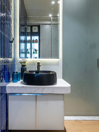 A detail of the modern blue-tiled bathroom in the Filigree House. The black vessel sink sits atop a white marble counter, creating a sharp, clean contrast that is both stylish and functional.